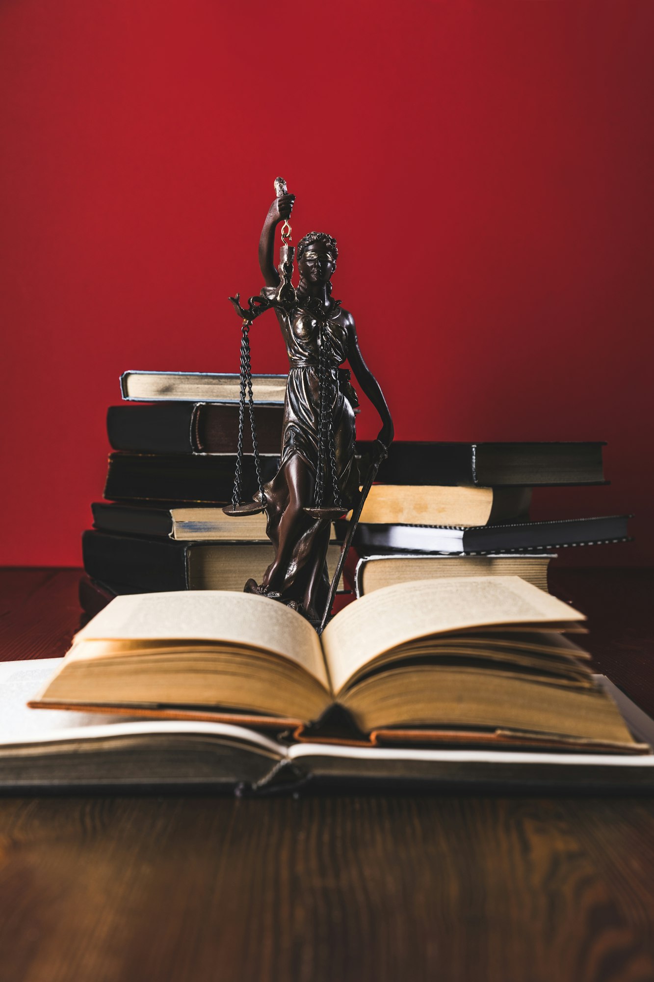 opened juridical books with lady justice statue on wooden table, law concept